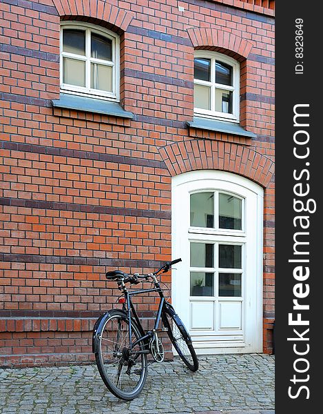 Old bike against a red wall and white door.