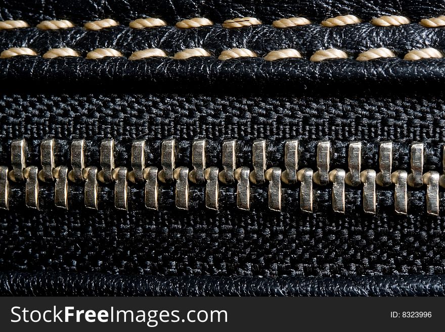 Zipper and black leather macro texture with light thread