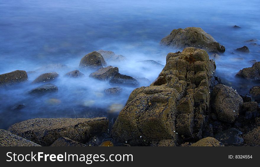 Rocks and sea by a rainy and windy day at Elgol port in scotland, isle of skye. Long exposure.