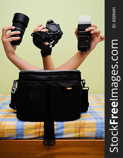 Camera bag with three hands sticking out from it holding various photography equipments. Camera bag with three hands sticking out from it holding various photography equipments.