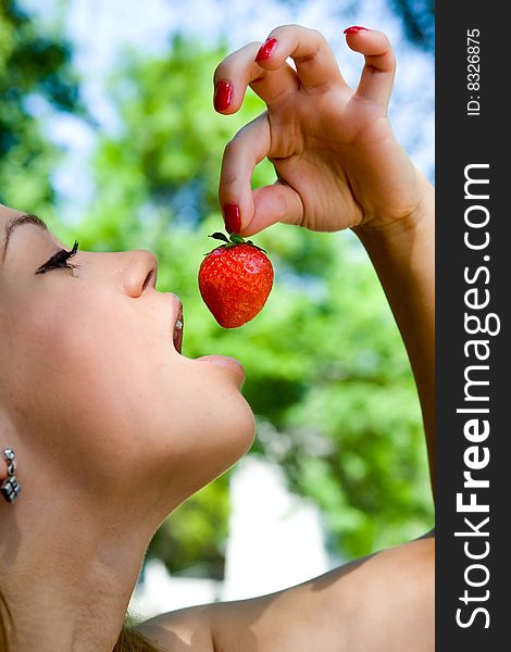 Portrait of the beautiful young girl on nature with strawberries