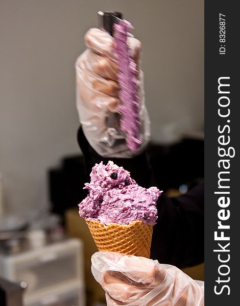 Person wearing latex gloves preparing ice cream on a cone