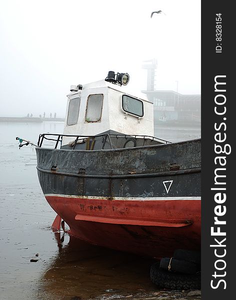 Fishing boat rests in frozen and misty harbor. Fishing boat rests in frozen and misty harbor
