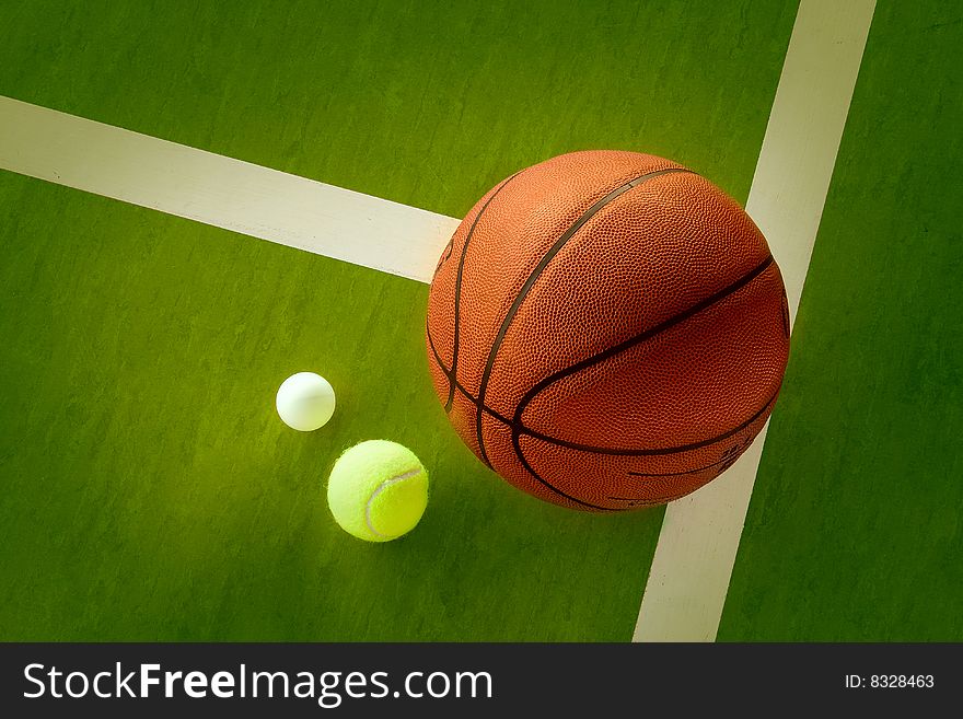 A basketball, a tennis ball and a Ping-Pong ball on the green background