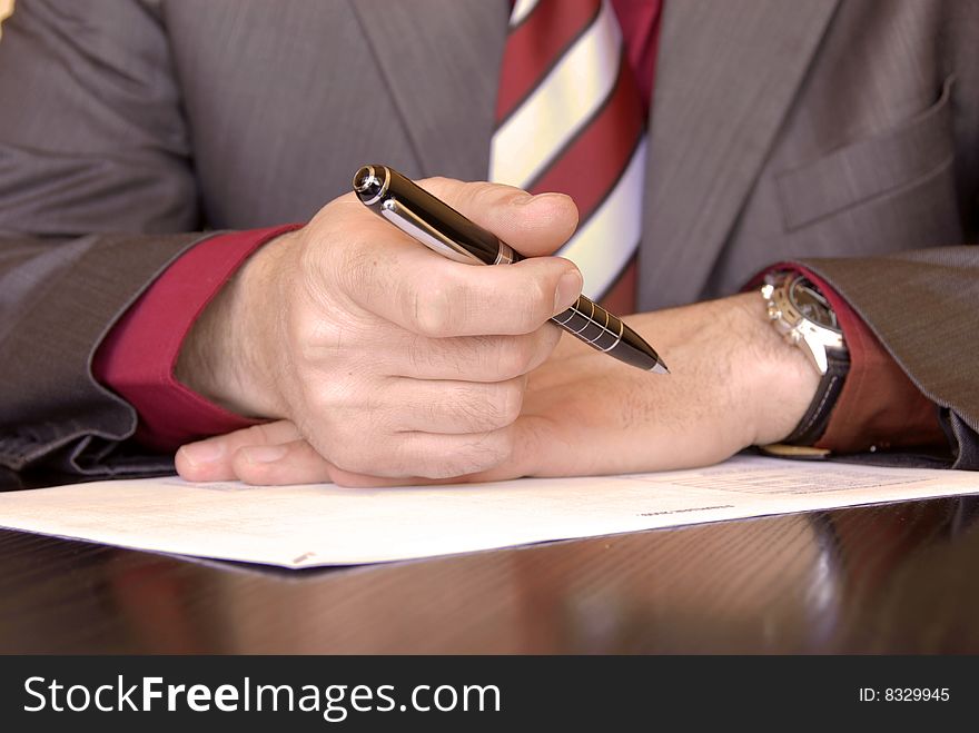 Businessman hands on desk signing a document. Businessman hands on desk signing a document