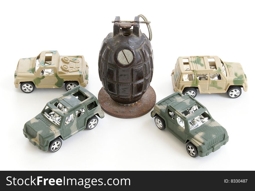 Four toy military vehicles surround a hand grenade. Four toy military vehicles surround a hand grenade.