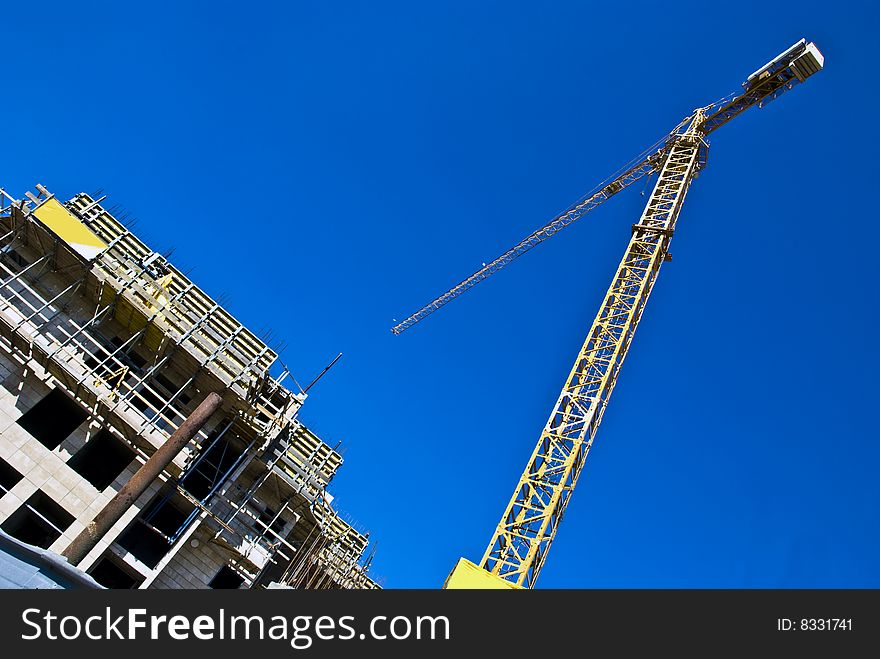 A multistory dwelling house under construction with a jib crane.