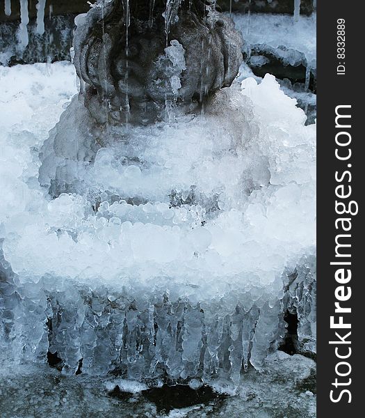 A close-up of a frozen fountain with multiple icicles.