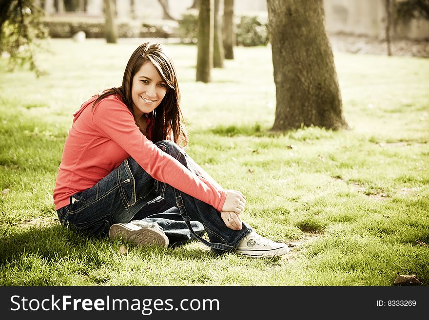 Smiling young woman sitting in the grass.