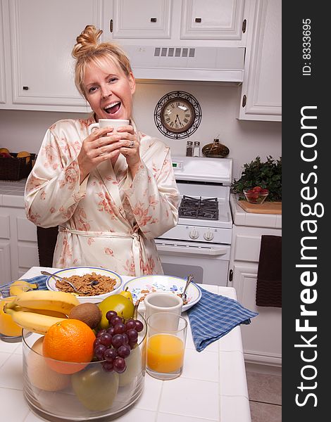 Expressive Woman In Kitchen with Fruit, Coffee, Orange Juice and Breakfast Bowls.