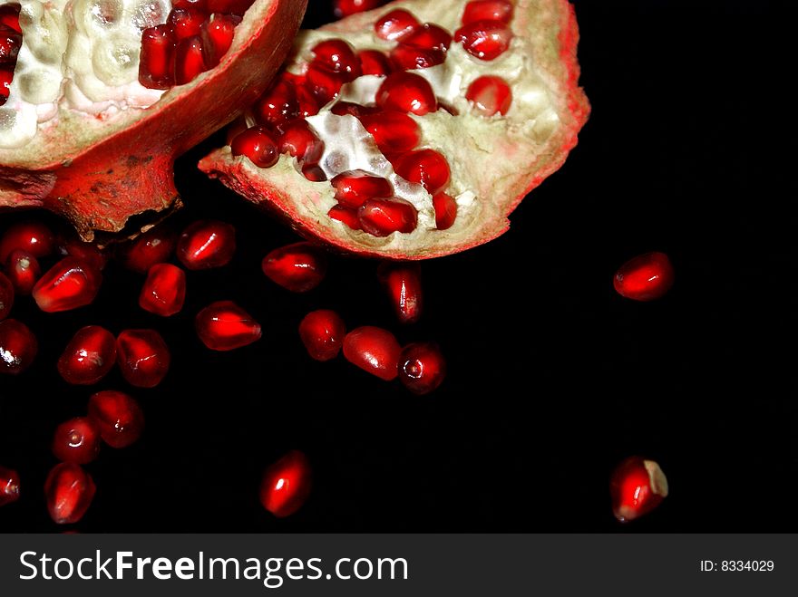 Grains of pomegranate, lie near the bisected fruit. Grains of pomegranate, lie near the bisected fruit