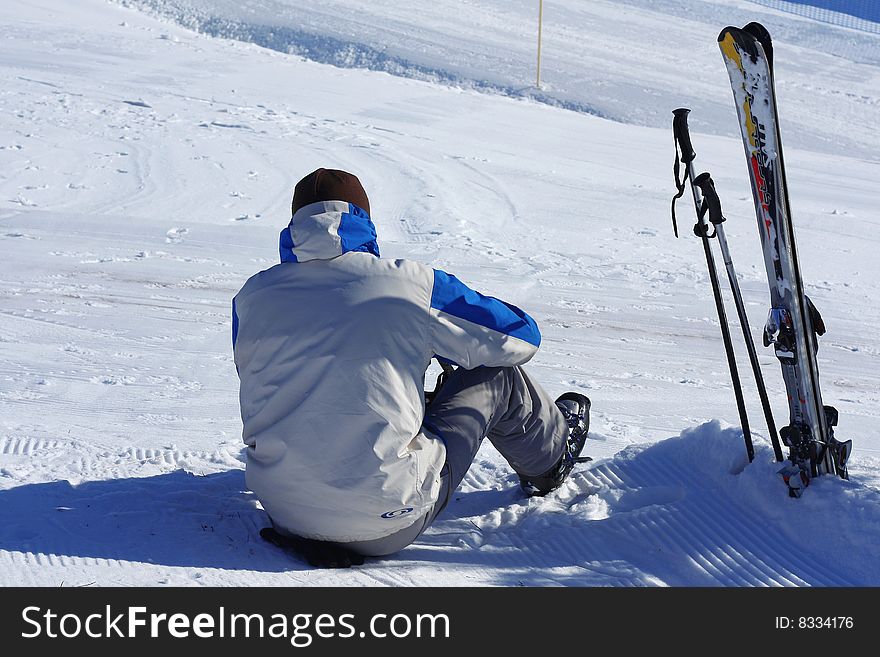 Tired ski rider sitting on snow