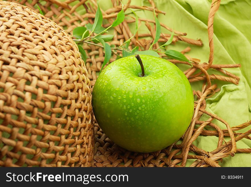 Apple and straw hat on a green background