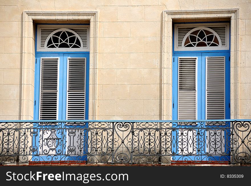 A classic balcony with shuttered twin blue framed doors