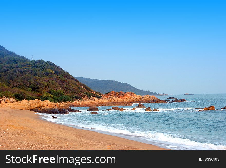Lonely wild beach, high blue sky, clear sea water, cliff and coastline, tropical seascape