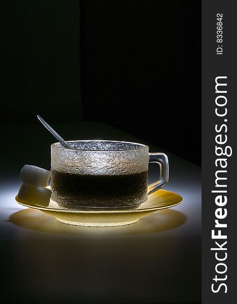 Cup of coffee in the dark, lighted by the spotligth