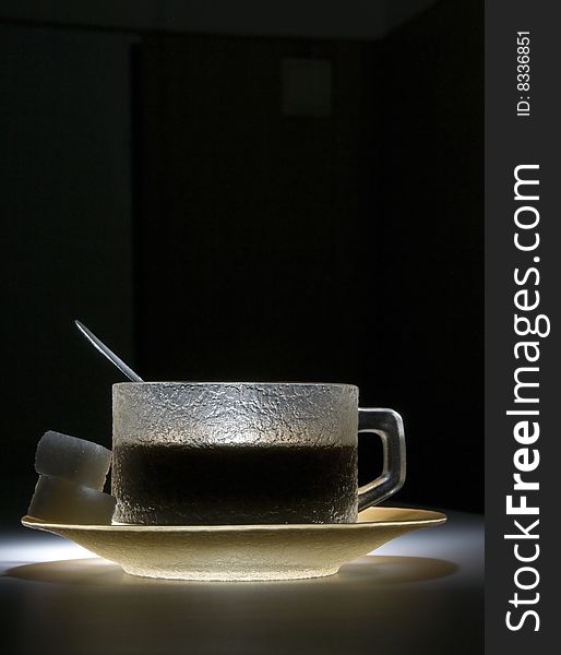 Cup of coffee in the dark, lighted by the spotligth