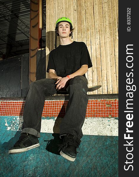 Skateboarder Sitting On His Board On Ramp