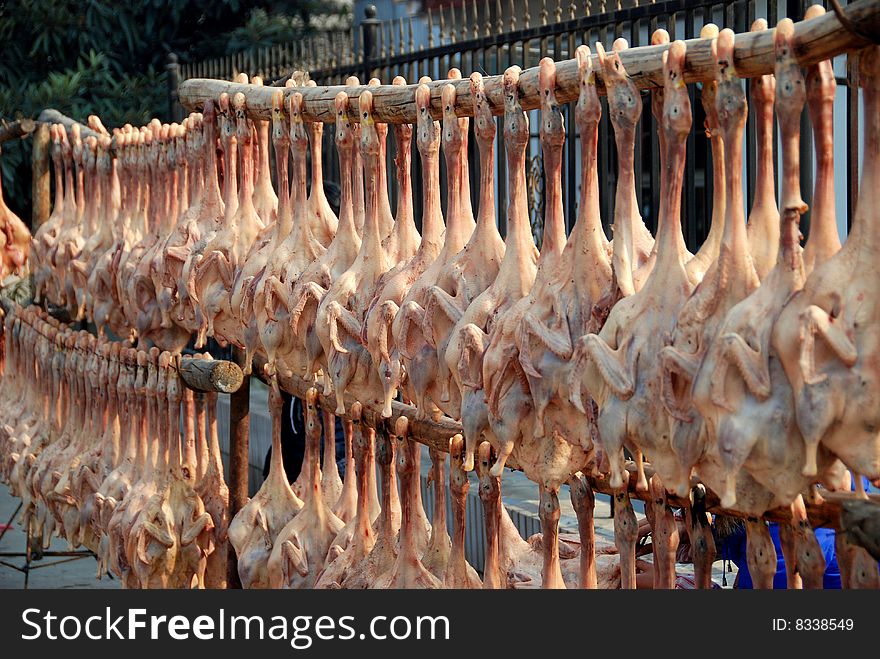 Hundreds of dried, pressed ducks hang from bamboo poles outside a meat market and are offered for sale, most especially during the Chinese Lunar New Year holiday - Lee Snider Photo. Hundreds of dried, pressed ducks hang from bamboo poles outside a meat market and are offered for sale, most especially during the Chinese Lunar New Year holiday - Lee Snider Photo.