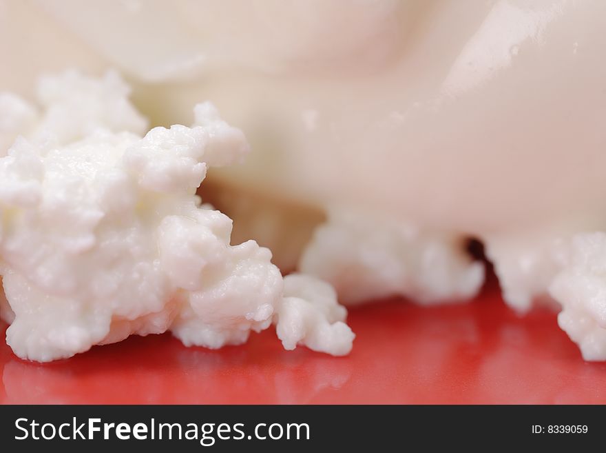 Cottage cheese with soured cream on the red plate. Close-up. Narrow depth of field. Cottage cheese with soured cream on the red plate. Close-up. Narrow depth of field.