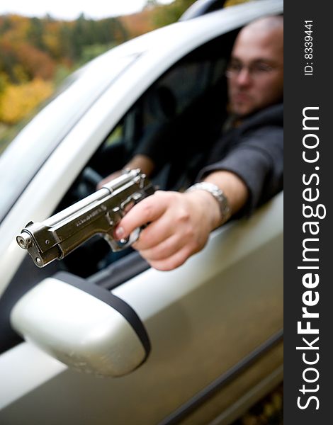 Angry man with gun driving car. Angry man with gun driving car