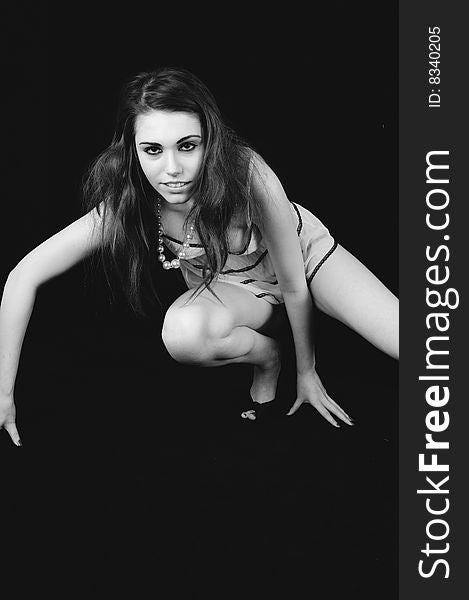 Female model in a movement style pose against a black background. Black and white image. Female model in a movement style pose against a black background. Black and white image.