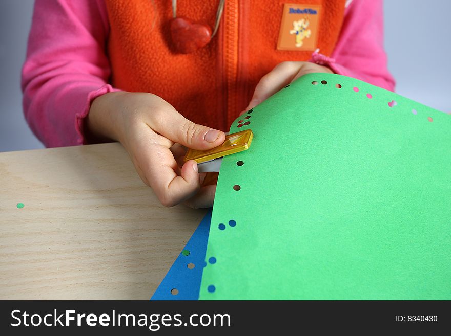 Little girl make holes in sheets of paper