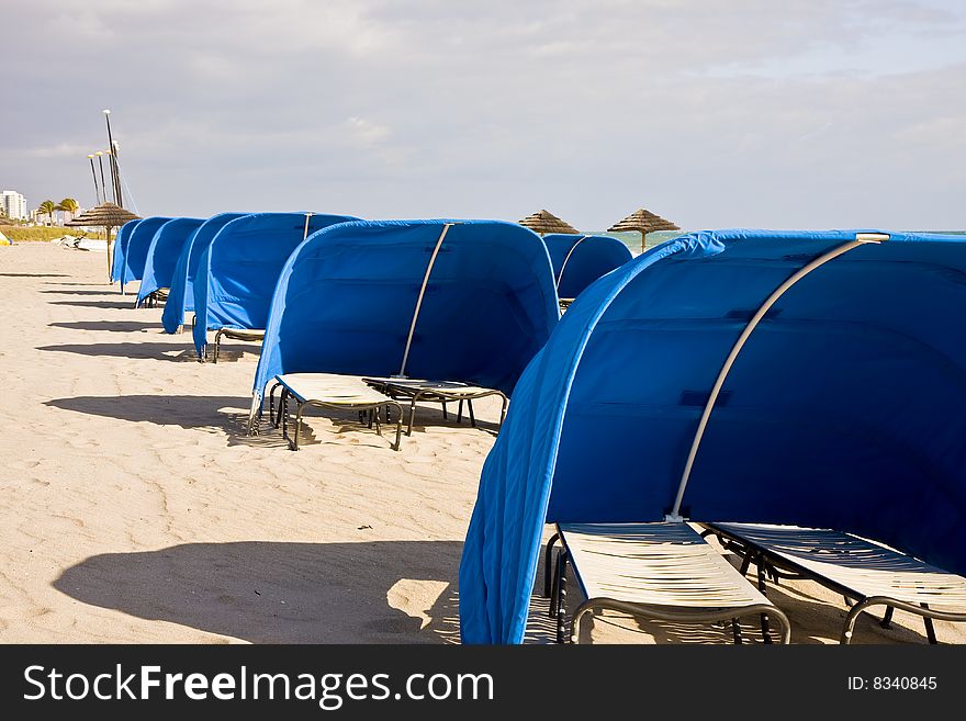 Blue Beach Shelters and Umbrellas on a beach on a cloudy day