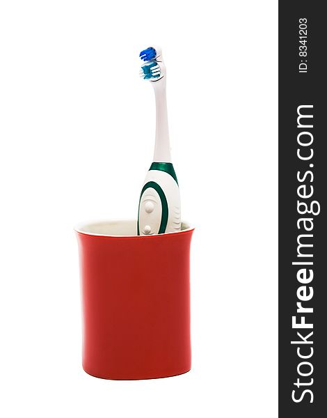 Toothbrush in a red glass on a white background. Toothbrush in a red glass on a white background