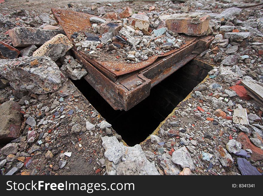 Manhole cover partially buried beneath rubble and debris. Manhole cover partially buried beneath rubble and debris.