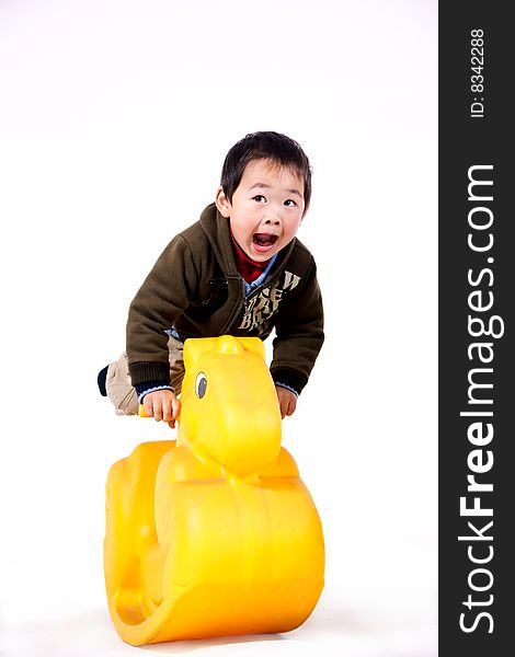 A picture of a little chinese boy riding a yellow plastic toy horse and having great fun. A picture of a little chinese boy riding a yellow plastic toy horse and having great fun