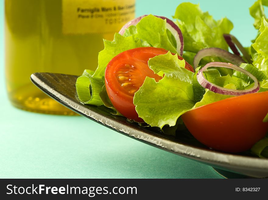 Healthy fresh salad on plate with bottle of olive on in background. Blue background. Healthy lifestyle. Healthy fresh salad on plate with bottle of olive on in background. Blue background. Healthy lifestyle.