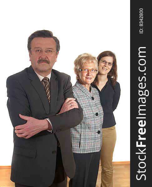 Small group of business people in business suits standing looking forward. Focus is on the mature man in front. Small group of business people in business suits standing looking forward. Focus is on the mature man in front.