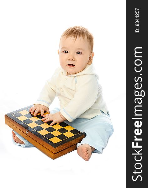 Cute ten months old baby sitting on the floor with a chessboard in his hands. Cute ten months old baby sitting on the floor with a chessboard in his hands