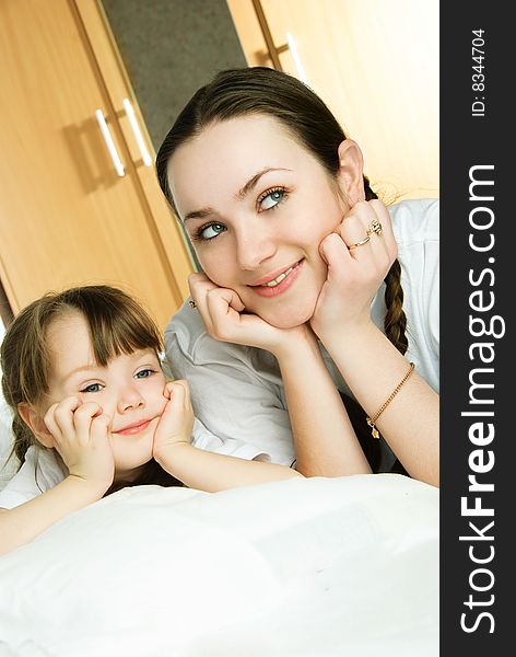 Beautiful young mother and her little daughter on the bed dreaming of something. Beautiful young mother and her little daughter on the bed dreaming of something