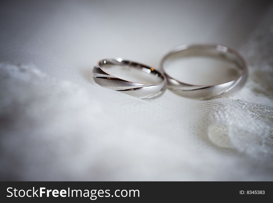 Wedding rings of white gold on lace background