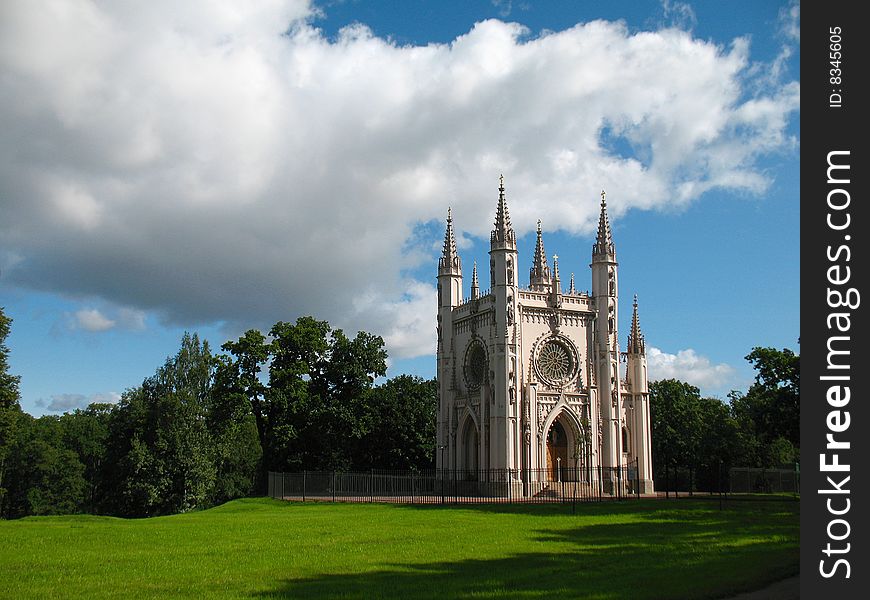 Gothic chapel on green glade whith blue sky