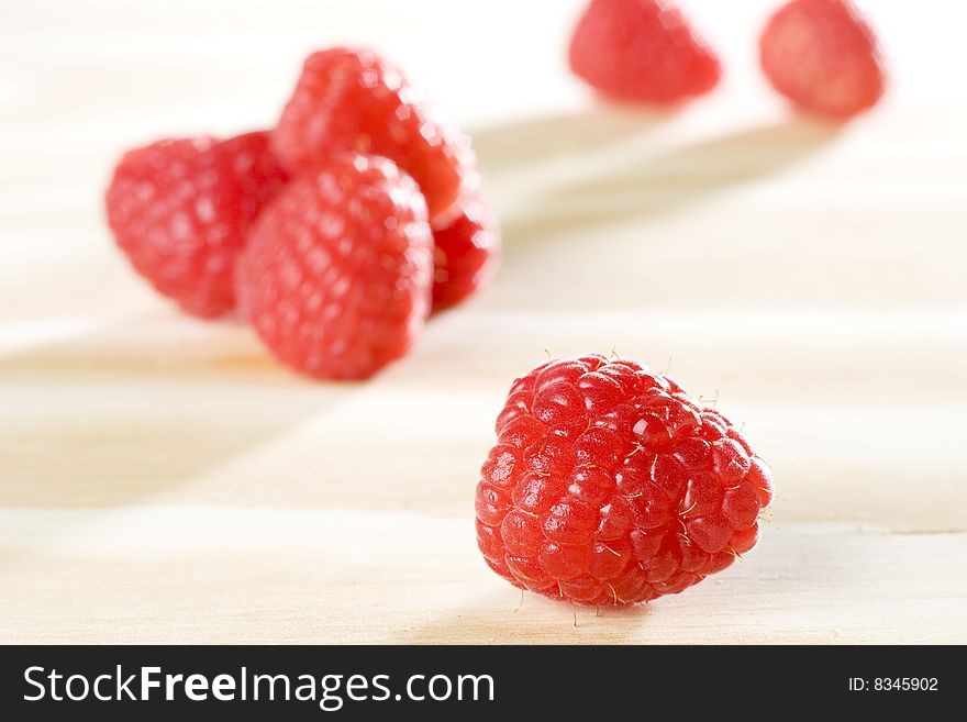 Fresh colorful raspberries on wooden background