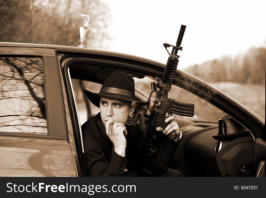 Man in car with cigar and rifle