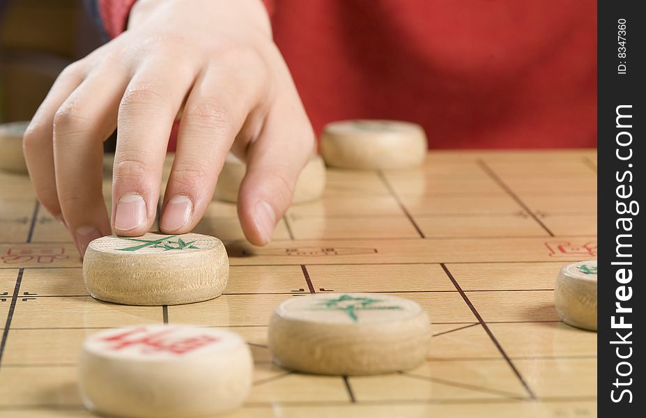 A boy is moving a piece of Chinese chess. A boy is moving a piece of Chinese chess.