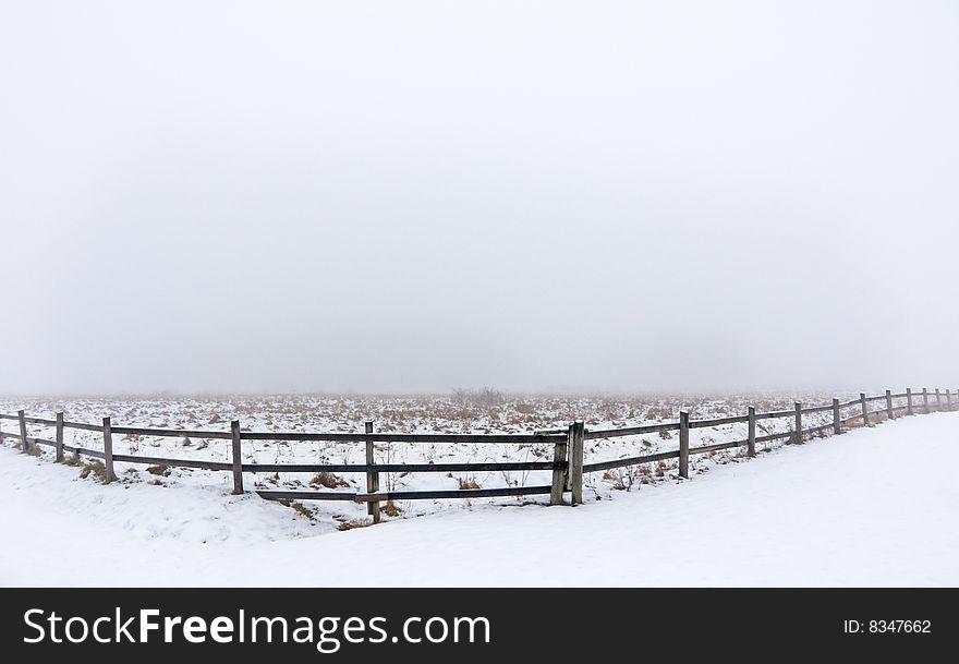 Wooden fence and a meadow on a foggy winter day. Wooden fence and a meadow on a foggy winter day