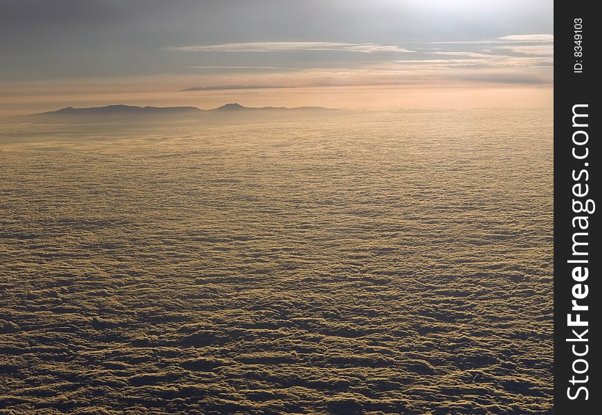 The sun declines above the clouds. A mountain is looming on the background. The sun declines above the clouds. A mountain is looming on the background.