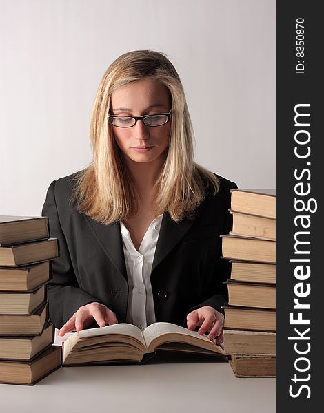 A young pretty woman reading a book and sitting on a table above a white background. A young pretty woman reading a book and sitting on a table above a white background