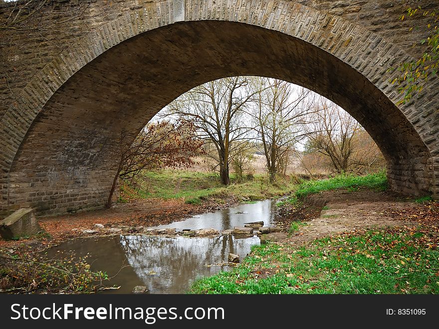 Old stone bridge through small river, autumn. Old stone bridge through small river, autumn