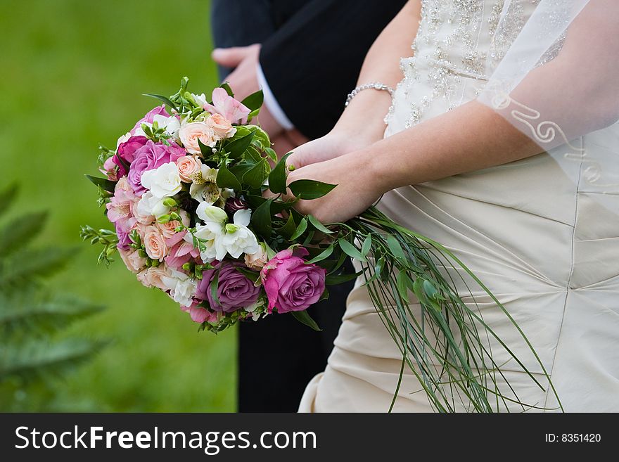 Bride and groom stand near each other with bouquet of roses. Bride and groom stand near each other with bouquet of roses