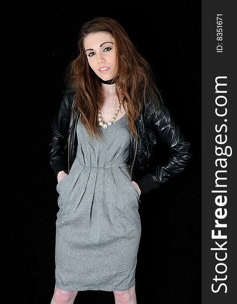 Female model standing in front of a black back ground with her hands in her pocket looking directly at the camera. Female model standing in front of a black back ground with her hands in her pocket looking directly at the camera