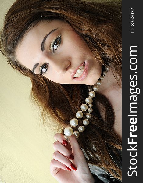 Female model pulling at her pearl necklace at an angled view. Female model pulling at her pearl necklace at an angled view