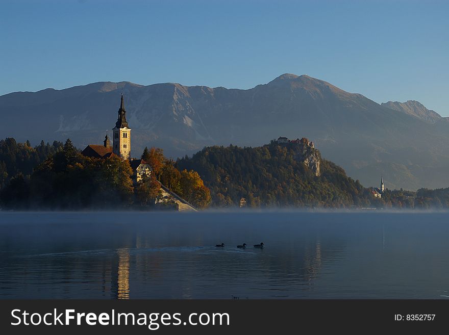 Lake Bled with church on island and castle on a rock in autumn morning
