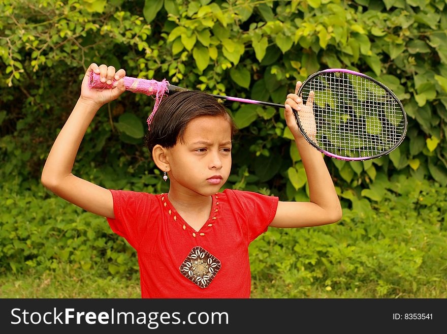 A girl with her badminton bat thinking seriously about something.