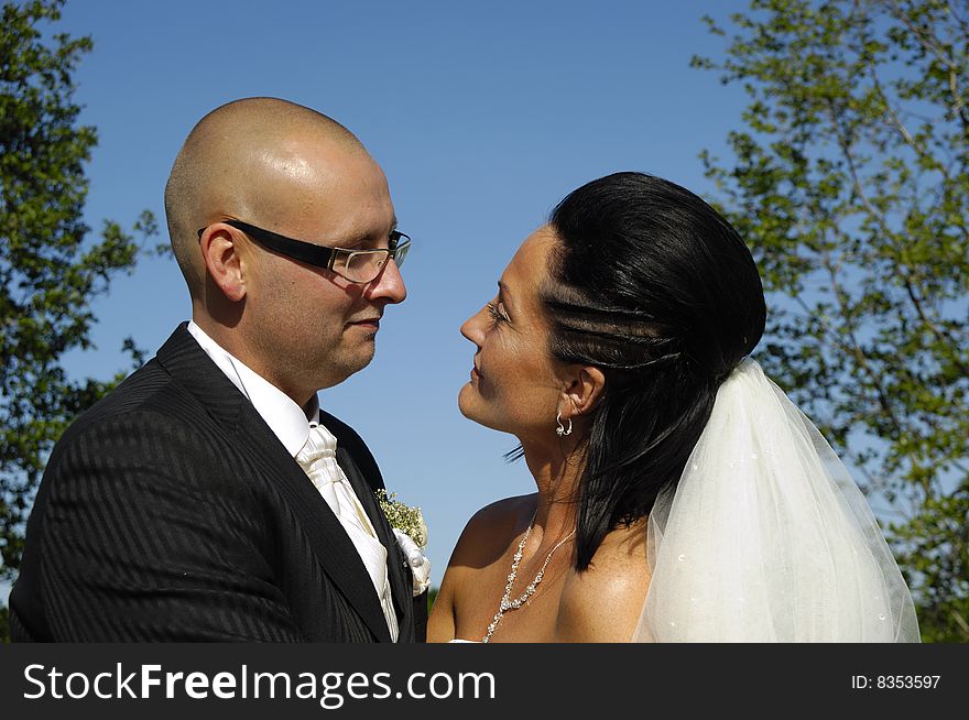 Bride and groom are standing close together looking at each other.